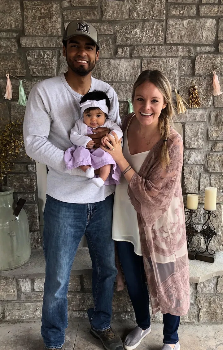 A family standing at home with their new baby