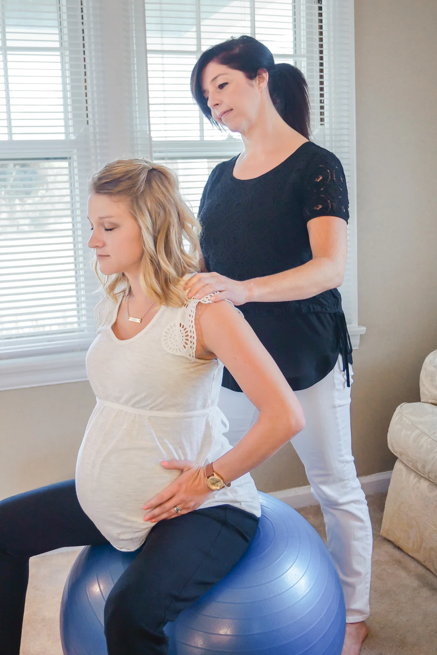 A pregnant client using a birth ball with hands-on support