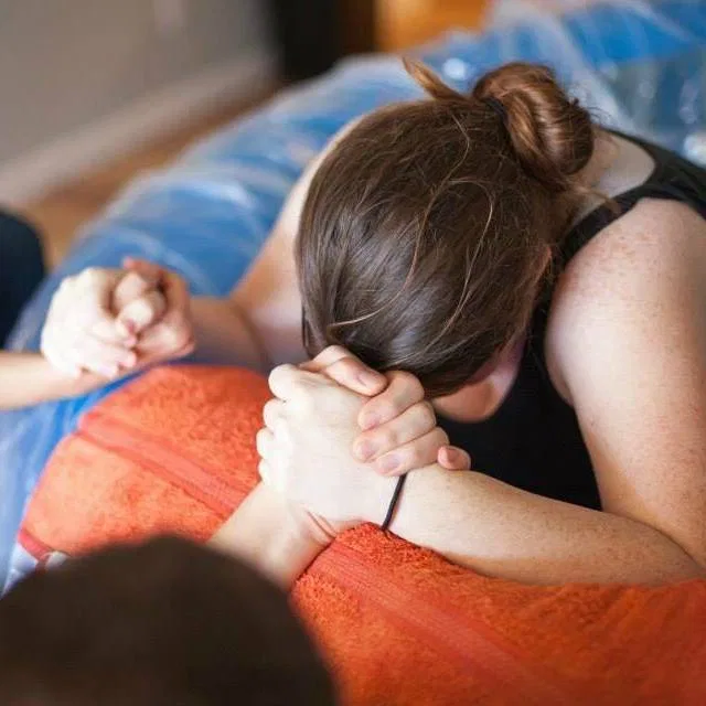 A laboring mother holding a support person’s hands
